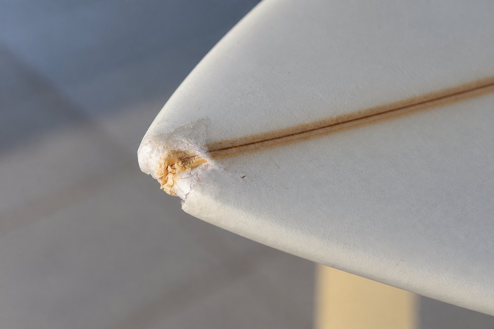 Punta de tabla con el laminado reventado y el foam a la vista